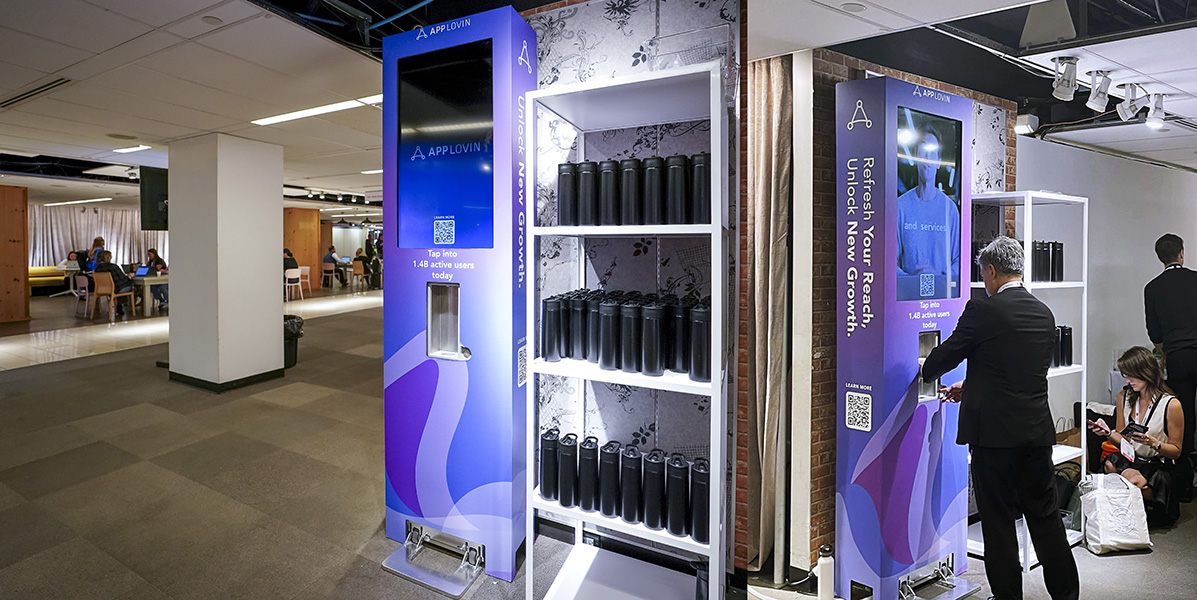 Custom-branded EVENTA Water stations for Advertising Week New York 2024 in office lobby with shelves of bottles.