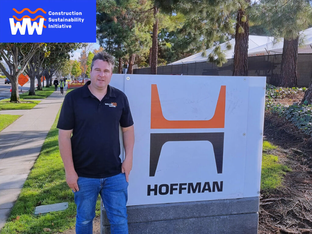 Man standing beside Hoffman sign on sidewalk.