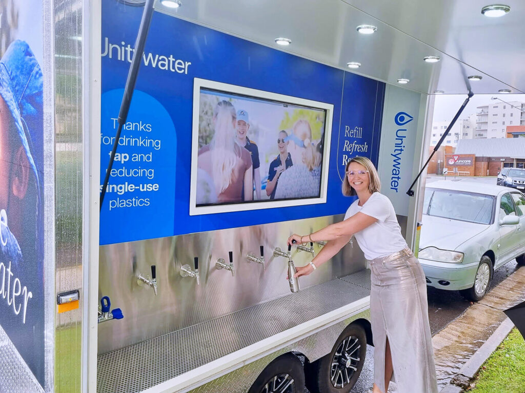 Woman refilling bottle at Unitywater station.