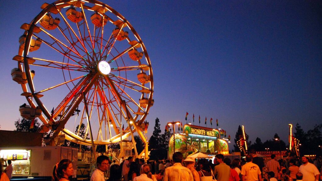 Carnival at night with Ferris wheel and crowd.