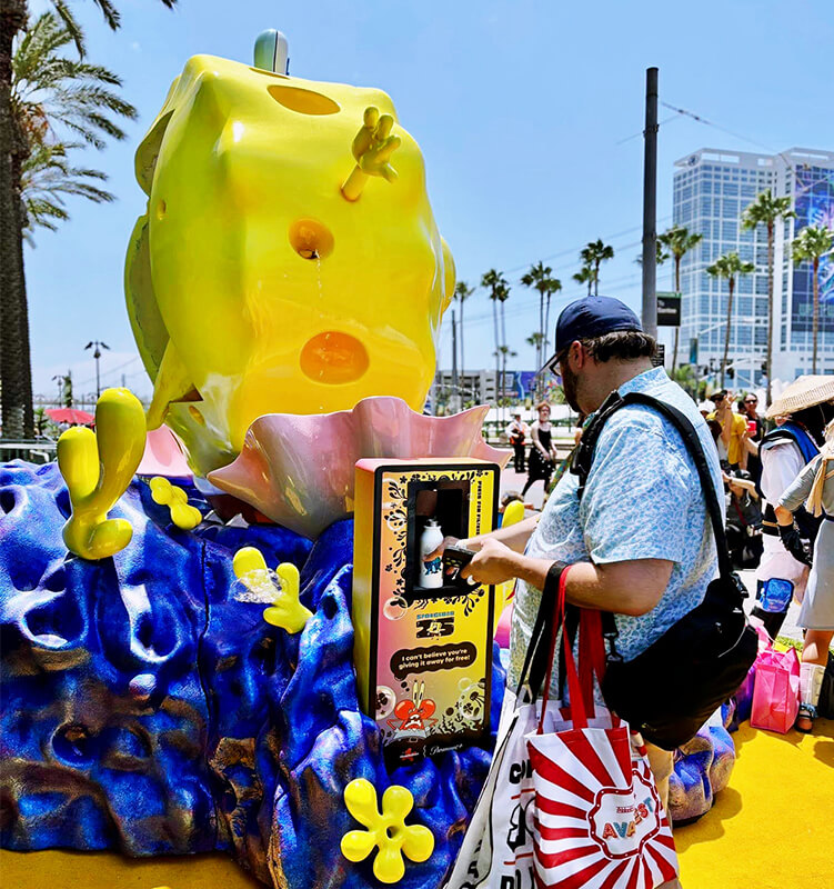 Man using vending machine near SpongeBob sculpture.