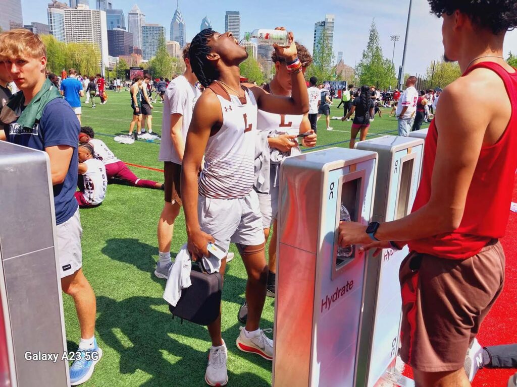 Athletes hydrating at sports event in sunny city park.