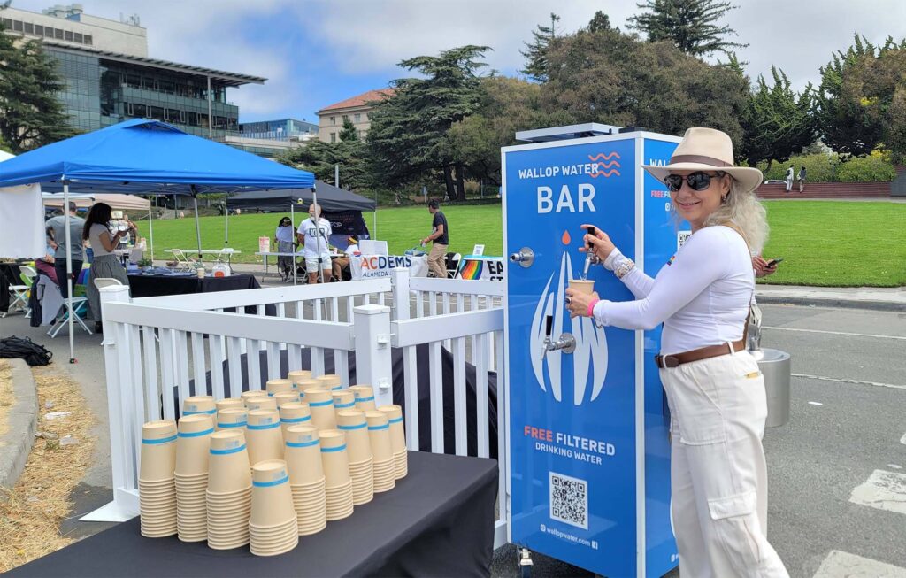 Woman using water station at outdoor event.