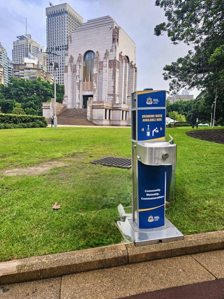 Drinking fountain near historical building in park.