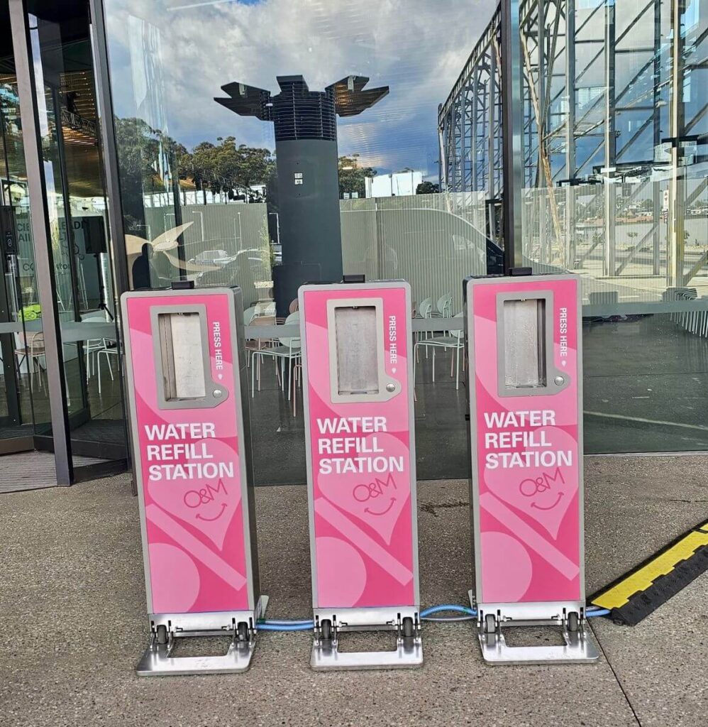 Three pink water refill stations outdoors.