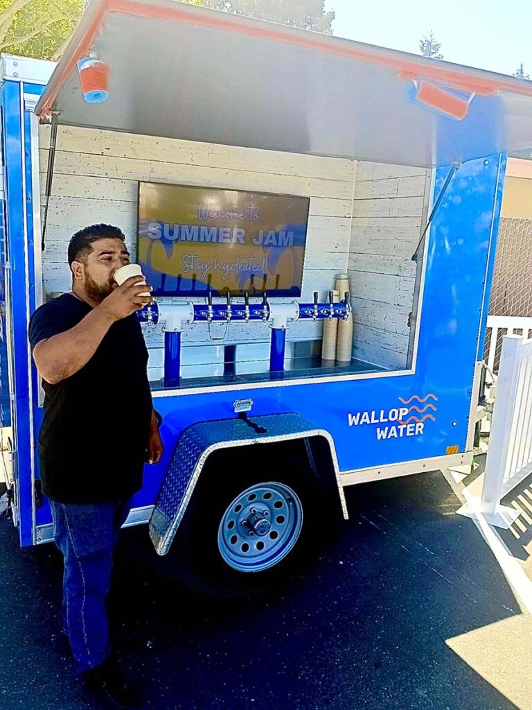 Man drinking from water stand at Summer Jam event.