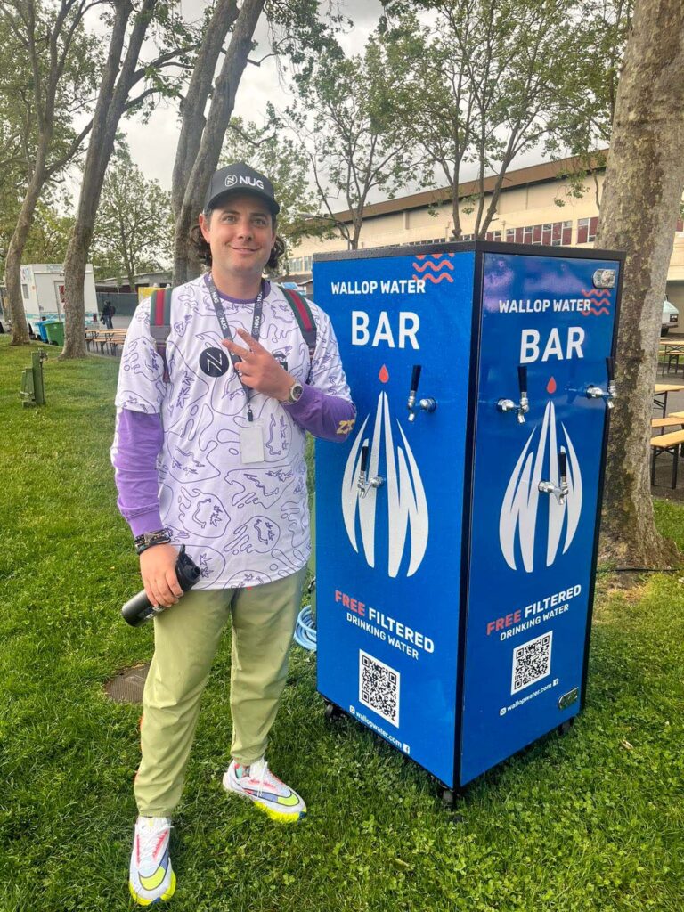 Person near outdoor water station on grassy area.