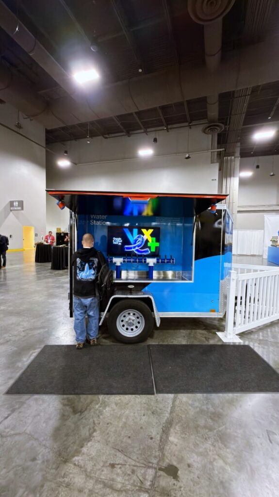 Man at blue water station trailer indoors