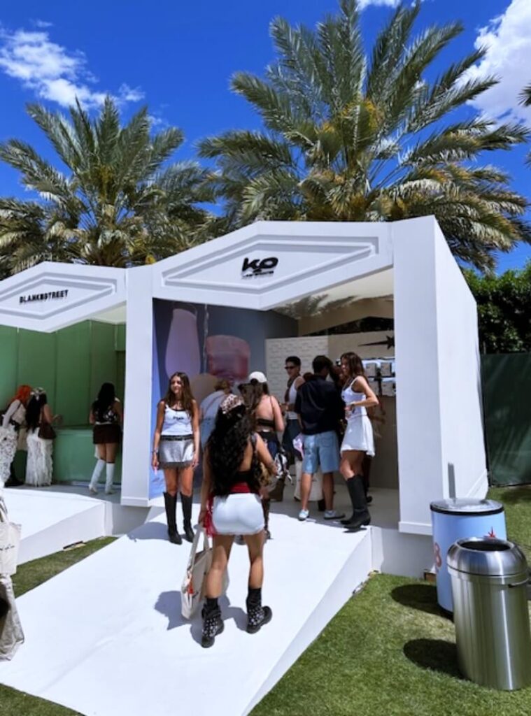 People entering white outdoor booth under palm trees