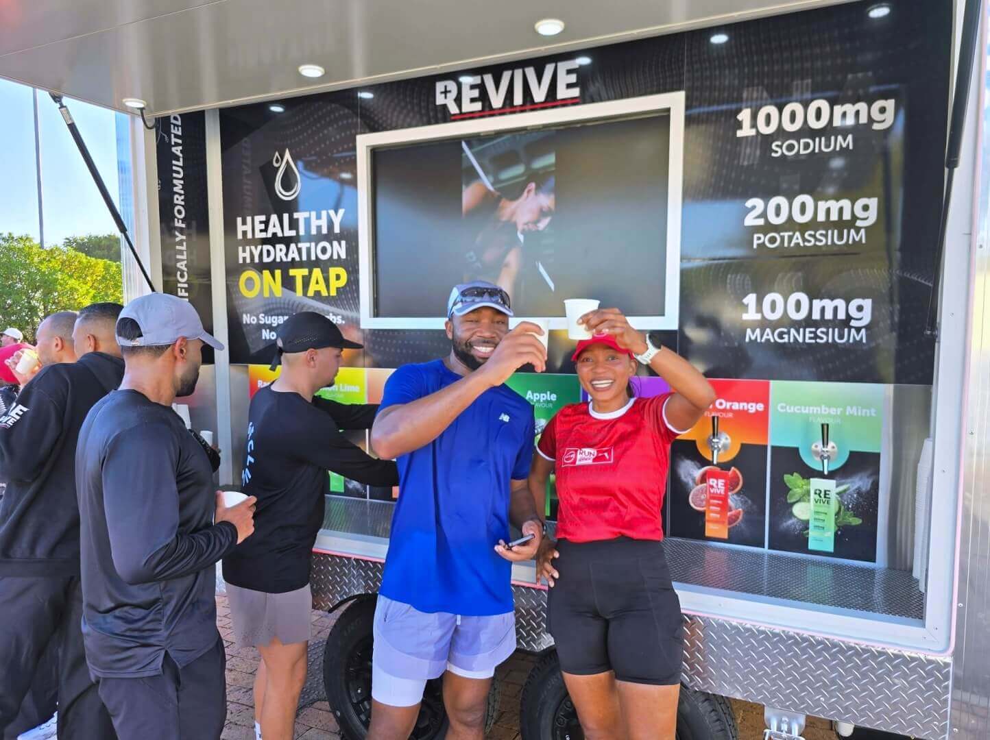 People toasting drinks at outdoor hydration stand
