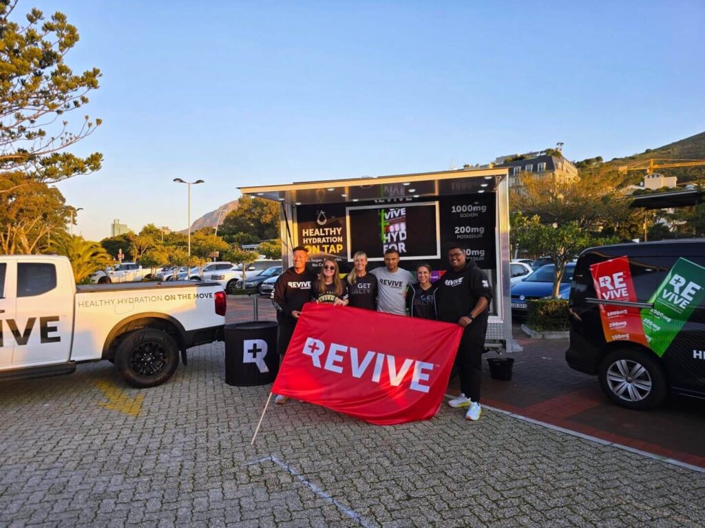 Team holding REVIVE banner by hydration truck