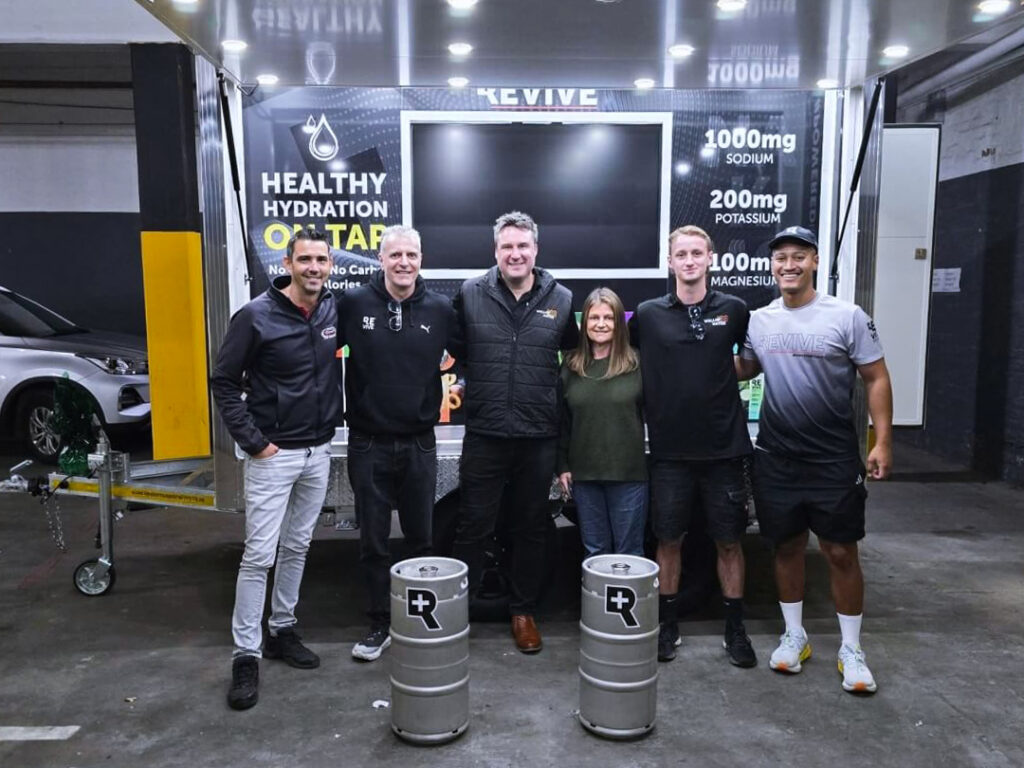 Six people posing at hydration product display